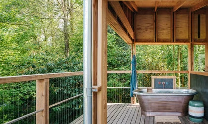 A freestanding copper bath at the sheltered woodland edge.